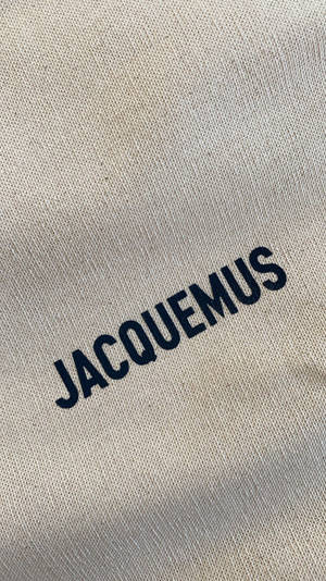 米色布料上以粗體刺繡的海軍藍 JACQUEMUS 標誌。 — 品牌 壁紙