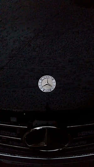 夜間燈光下深色引擎蓋上的賓士標誌。 — Mercedes Benz C300 壁紙