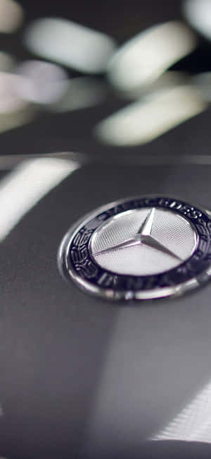 Mercedes-Benz 標誌在黑色引擎蓋上，背景模糊。 — Pixel 9 Pro 壁紙