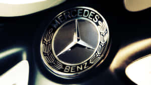 近距離拍攝汽車輪圈上的 Mercedes-Benz 標誌，帶有金屬光澤和溫暖燈光。 — Mercedes-Benz 壁紙