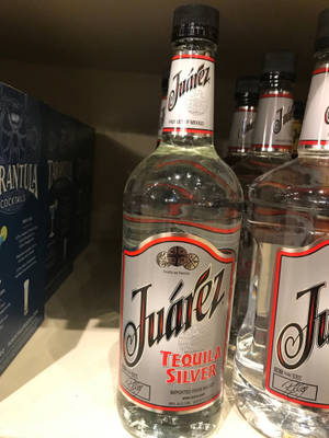 商店貨架上排列的Juarez龍舌蘭酒瓶，附近有一個雞尾酒盒。 — 銀色 壁紙