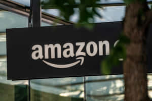 透過玻璃建築附近的樹葉看到的Amazon標誌 — 桌面 壁紙