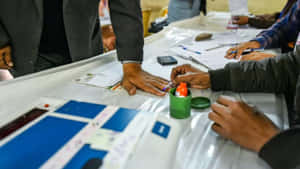 在投票站，工作人員在附近為選民手指沾墨。 — 選舉 壁紙
