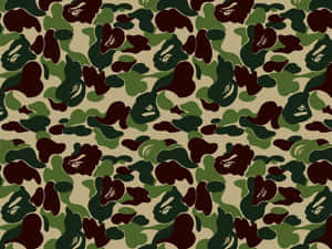 迷彩壁紙，以綠色、棕色和米色重複猿臉圖案。 — BAPE 標誌 壁紙