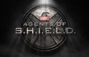 黑暗煙霧背景中聚光燈下的S.H.I.E.L.D.標誌與Marvel標誌 — 漫威標誌 壁紙
