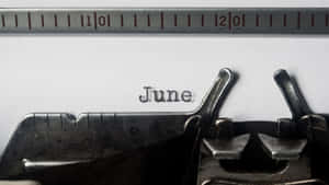 復古打字機在白色紙上打出「June」一詞，上面有金屬尺。 — 六月 壁紙
