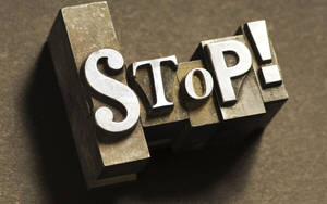 金屬活字塊拼出stop，在棕色表面投下戲劇性陰影 — 字體排印 壁紙
