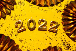 金色2022蠟燭被金屬扇和五彩紙屑包圍在黃色背景上 — 新年 壁紙