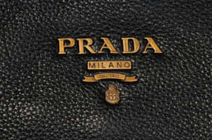 金色Prada Milano標誌在黑色紋理皮革上。 — 普拉巴斯 壁紙