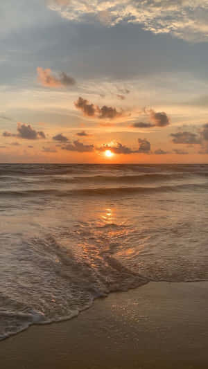 夕陽映照海洋，海浪沖刷沙灘。 — 日落 壁紙