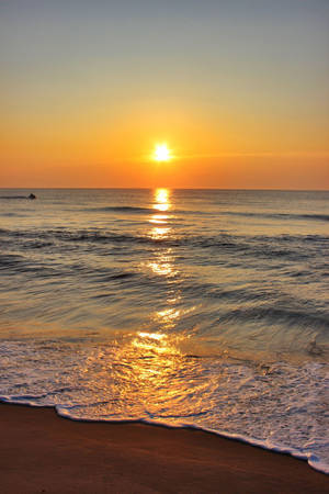 海上夕陽，沙灘上的海浪，遠處的游泳者 — 日落 壁紙