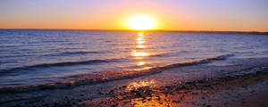 夕陽下的海洋，波浪拍打卵石海灘 — 海洋 壁紙