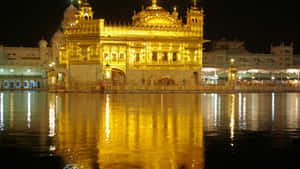 金色寺廟在夜間亮燈，水面倒影 — 金廟 壁紙