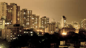密集市區的夜景，窗戶發光，樹木深色。 — 孟買 壁紙