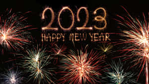 煙火在發光的金色文字周圍爆炸，文字寫著 2023 Happy New Year。 — 慶祝 壁紙