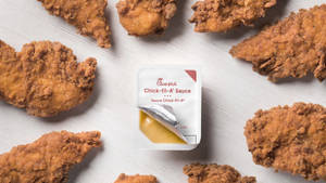 金黃色炸雞塊排列在 Chick-fil-A 醬料包周圍，置於木頭上。 — 沙拉 壁紙