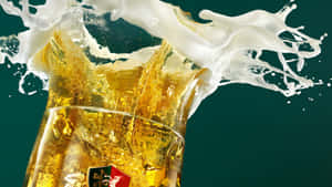 金黃色啤酒帶有白色泡沫從玻璃杯中飛濺，背景為深綠色。 — 啤酒 壁紙