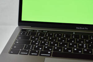 銀色 MacBook Pro，配備西里爾字母鍵盤及顯示計時器的綠色螢幕。