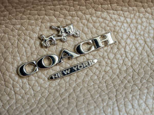 米色皮革上的銀色Coach標誌，帶有馬和馬車。 — 教練 壁紙
