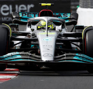日落比賽期間，梅賽德斯一級方程式賽車在賽道上。 — F1 iPhone 壁紙