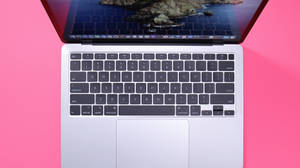 粉紅色表面上銀色筆記型電腦鍵盤，顯示海洋桌布。 — MacBook Air 壁紙