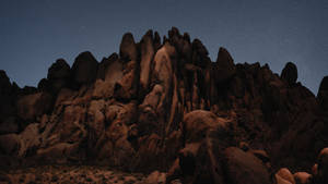 崎嶇沙漠岩層上方的星空夜空。 — macOS Mojave 壁紙