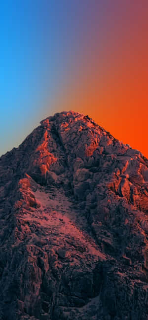 岩石山峰在日落色彩中閃耀，映襯著藍色天空。 — 自然 iPhone 壁紙