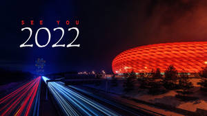 安聯球場夜景，紅燈和劃過的車流，下方有「SEE YOU 2022」文字。 — 卡達 壁紙
