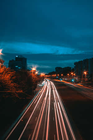 藍天下夜間城市高速公路上的汽車燈光條紋。 — Huawei MatePad 壁紙