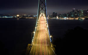 夜間的橋樑，帶有汽車燈光軌跡和背景的城市天際線。 — 加州 壁紙