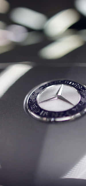 黑色汽車引擎蓋上帶有光線反射的 Mercedes-Benz 標誌特寫。 — Motorola Edge 壁紙