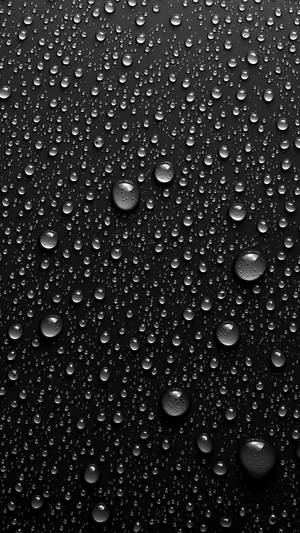 黑色表面上反射光線的雨滴特寫。