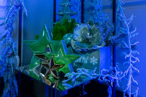 節日裝飾，在藍色燈光下的鏡面表面上有綠色星星和結霜的樹枝。 — 聖誕美學 壁紙