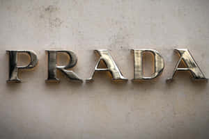 拋光金屬製成的Prada標誌字母在米色牆上。 — 普拉巴斯 壁紙