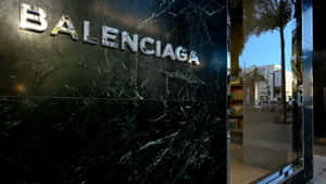 Balenciaga 商店入口，深色大理石牆和玻璃窗映照著棕櫚樹和街道。 — 巴黎世家 壁紙