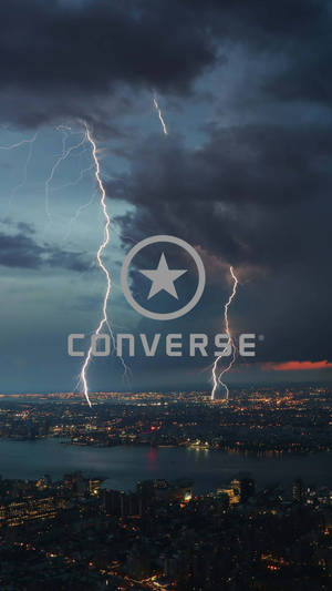 夜晚城市上空閃電劃過，燈光在水面上反射。 — Converse 標誌 壁紙