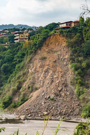 建在陡峭侵蝕山坡上的房屋，俯瞰著多雲天空下的河流。 — 風景 壁紙