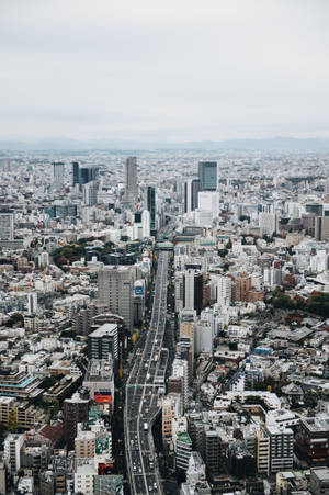 灰色天空下，高樓大廈和繁忙高速公路的密集城市鳥瞰圖。 — 東京 壁紙