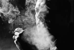 男人吸煙，煙霧在臉龐周圍旋轉，黑白風格。 — 抽菸 壁紙