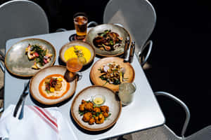 在溫暖的夕陽下，擺放著五道美食佳餚和飲品的餐桌。 — 壽司 壁紙