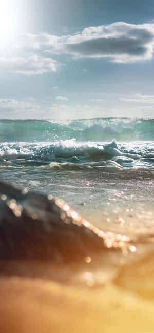 陽光照耀的海浪拍打沙灘，前景呈現金色散景。 — 海灘 壁紙