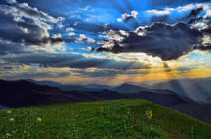 陽光穿過雲層照耀在山脈上，草地青青。 — 自然風景動圖 壁紙