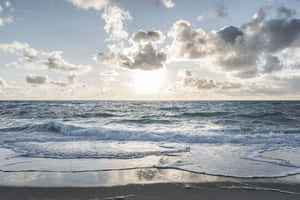 夕陽映照海洋，海浪在散落的雲層下拍打沙灘 — 海灘 壁紙