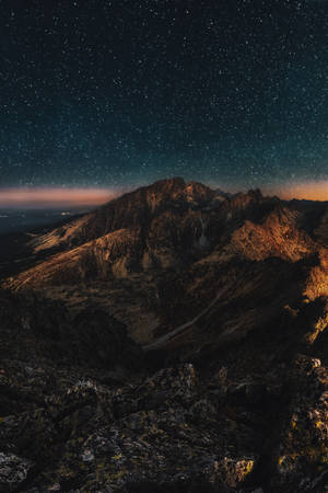 暮色中星光映照的山脈，下方遠處城市燈光。 — 星星 壁紙