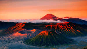 火山在日出色彩中發光，下方有雲 — 印尼 壁紙