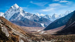 積雪的山峰在明亮的藍天下，從岩石山谷中拔地而起。 — 雪山 壁紙