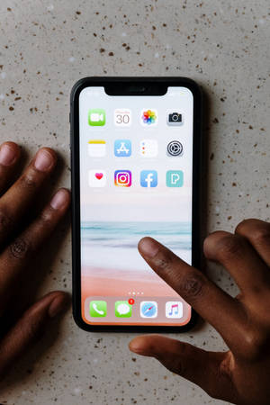 在斑點表面上使用帶有沙灘桌布的智慧型手機的雙手。 — 插畫 iPhone 壁紙