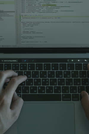 一個人在深色主題螢幕的筆記型電腦鍵盤上輸入程式碼。 — 暗黑美學電腦 壁紙