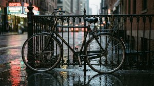 復古腳踏車停在夜晚濕透的城市街道上，帶有霓虹倒影。 — 腳踏車 GIF 壁紙