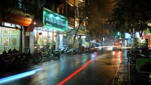 夜晚的城市街道，濕漉漉的路面反射著霓虹燈光和行駛中的汽車。 — 台北 壁紙